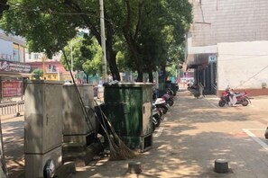 A street with parked motorcycles, a row of trees, and utility boxes.