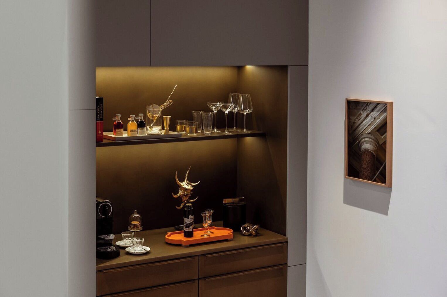 A bar area with shelves of bottles and glasses, a decorative horn, and a framed picture on the wall.