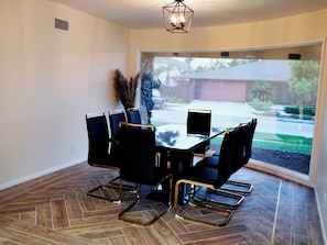 Enjoy meals in this stylish dining area with a large table and six chairs, surrounded by a view of the outdoors.