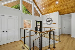 A spacious interior with a wooden staircase, white walls, and a view of greenery outside. - Tan Lines & Good Times, 6 bed/8 bath-Water Front,Private Dock, Hot tub, Gameroom (Morley)