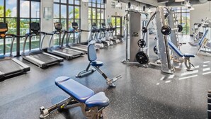 Un gimnasio con cintas de correr, máquinas de pesas y un banco.