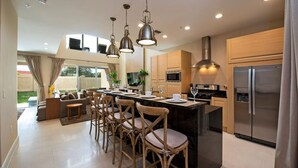 Una cocina moderna con una isla central, taburetes de bar y electrodomésticos de acero inoxidable.