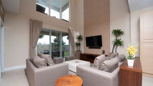 A spacious living room with a sofa set, a coffee table, and a flat-screen TV mounted on the wall. - 4BD luxury All suites home with BBQ near Disney (Kissimmee)