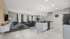 A modern kitchen with a central island, white cabinetry, and a built-in dishwasher. - Incredible 4BD home with Pool and BBQ near Disney (Kissimmee)
