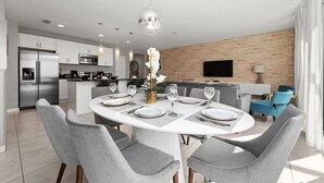 A modern kitchen with stainless steel appliances, a dining area with grey upholstered chairs, and a brick accent wall. - Incredible 4BD home with Pool and BBQ near Disney (Kissimmee)
