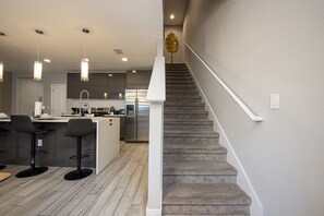 A modern kitchen with a central island, bar stools, and a stainless steel refrigerator. - 4BD Amazing Home with Pool and BBQ minutes from Disney (Kissimmee)
