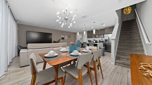 Ein modernes Wohnzimmer mit Essbereich, einer Küche und einer Treppe.