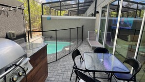 Eine Terrasse im Freien mit Grill, Sitzgelegenheit und Schwimmbad.