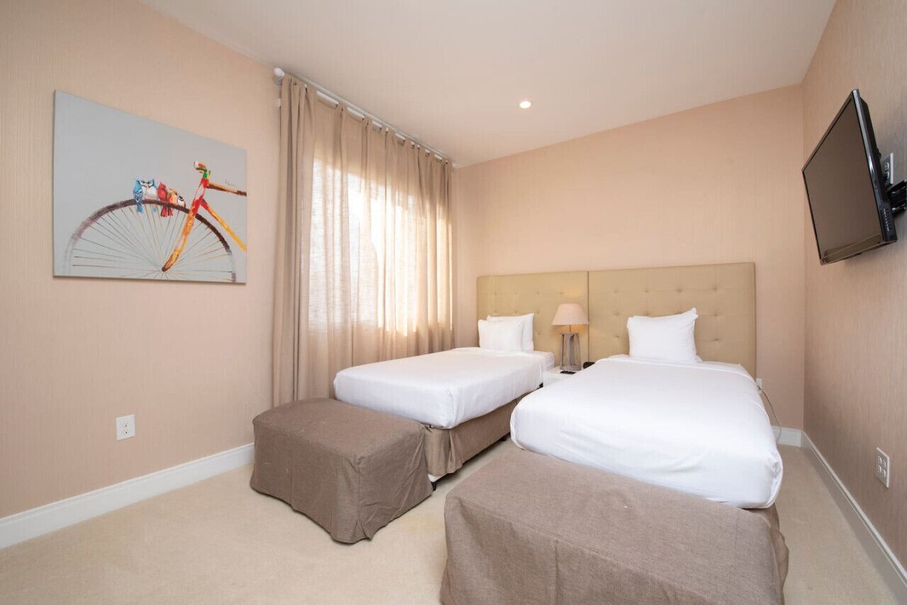 Una habitación de hotel con dos camas, un televisor montado en la pared y un cuadro de una bicicleta en la pared.