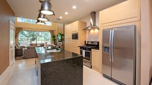 Una cocina moderna con encimeras de granito, electrodomésticos de acero inoxidable y armarios de madera.