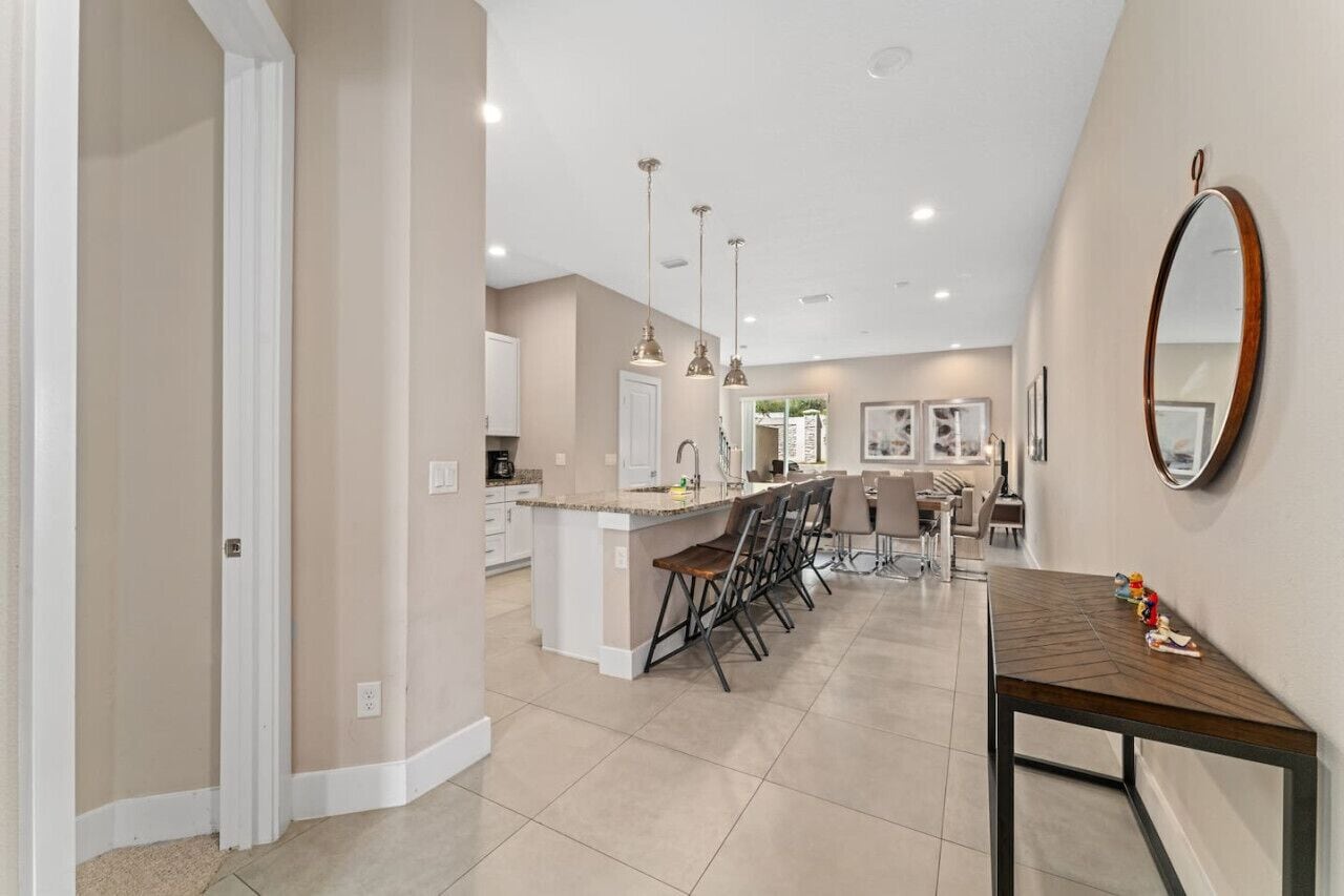 A spacious kitchen with a central island, pendant lighting, and a dining area with bar stools.
