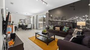 Een moderne woonkamer met een stadsgezicht muurschildering, een bijzettafeltje en een bank met decoratieve kussens.