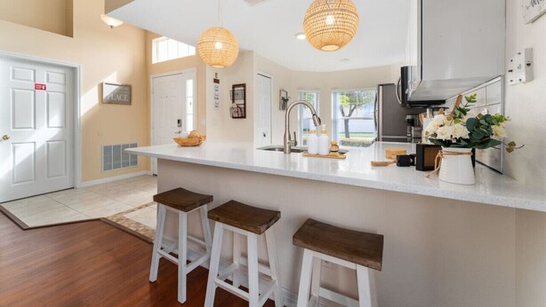 Una cocina moderna con una isla grande, luces colgantes y vistas al exterior.