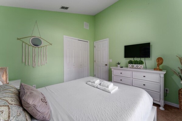 A bedroom with a bed, a dresser, a television, and a wall-mounted decoration. - 4BD Home Toy Story Mickey with Pool and Game Room (Kissimmee)