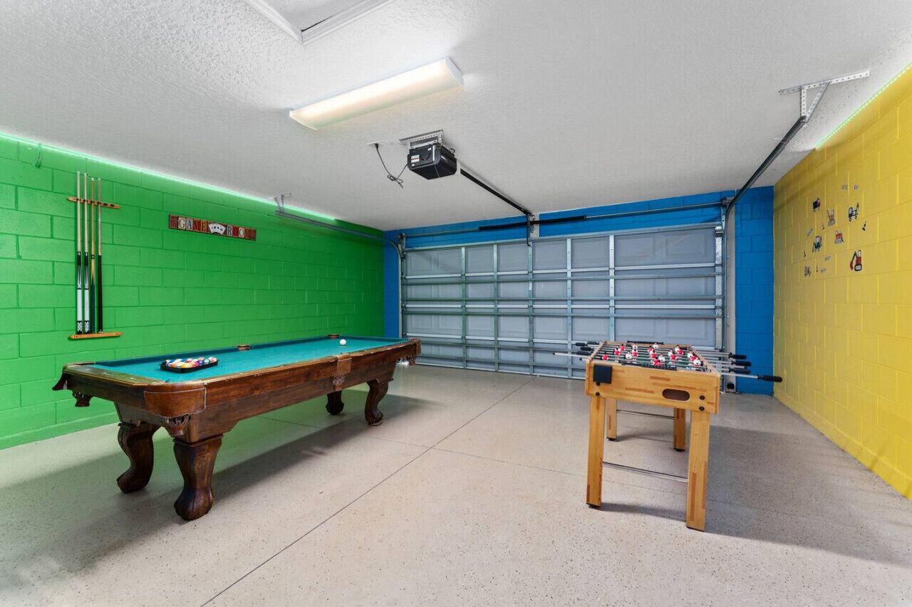 Una habitación con mesa de billar, mesa de futbolín y puerta de garaje.