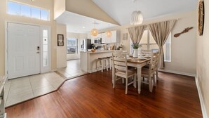 Una cocina amplia con una isla central, una mesa de comedor de madera y sillas. Hay un ventanal que proporciona luz natural y vistas al exterior.