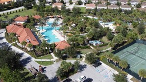 Vista aérea de una zona residencial con una gran piscina rodeada de casas y palmeras.