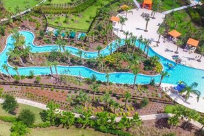 An aerial view of a resort with a winding pool, palm trees, and sun loungers. - 6BD Home with Game Room Sleeps 12 and Pet Friendly (Davenport)