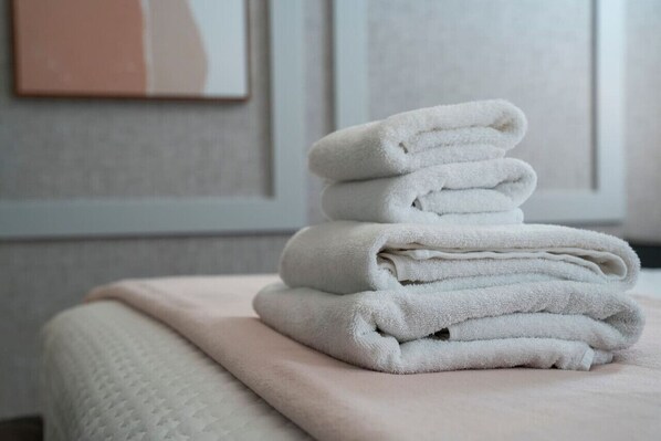 A stack of folded towels on a bed with a textured blanket.