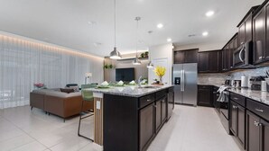 A modern kitchen with dark cabinetry, stainless steel appliances, and a central island.