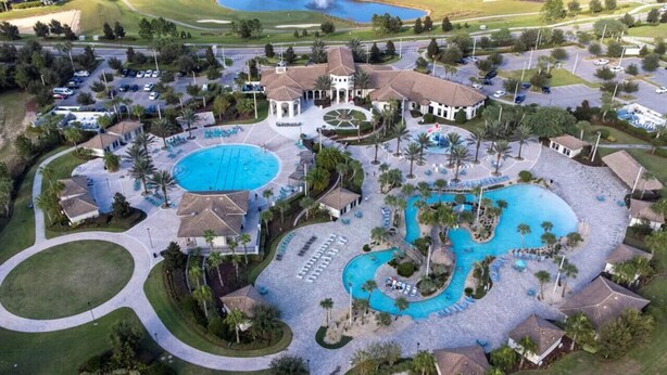 Vista aérea de um resort com várias piscinas, campo de golfe e amplo estacionamento.