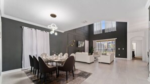 Uma sala de estar espaçosa com uma mesa de jantar, cadeiras e um sofá.