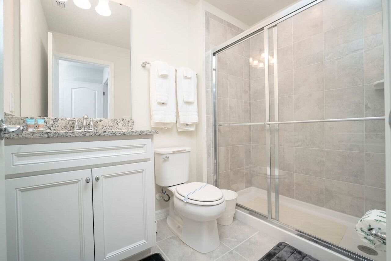 A bathroom with a toilet, sink, and shower area.