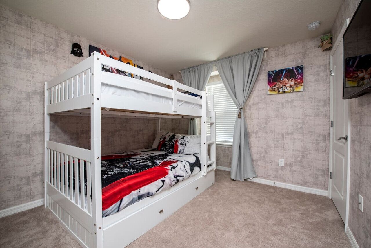 Une chambre avec un lit superposé, une fenêtre, des rideaux et une affiche accrochée au mur.