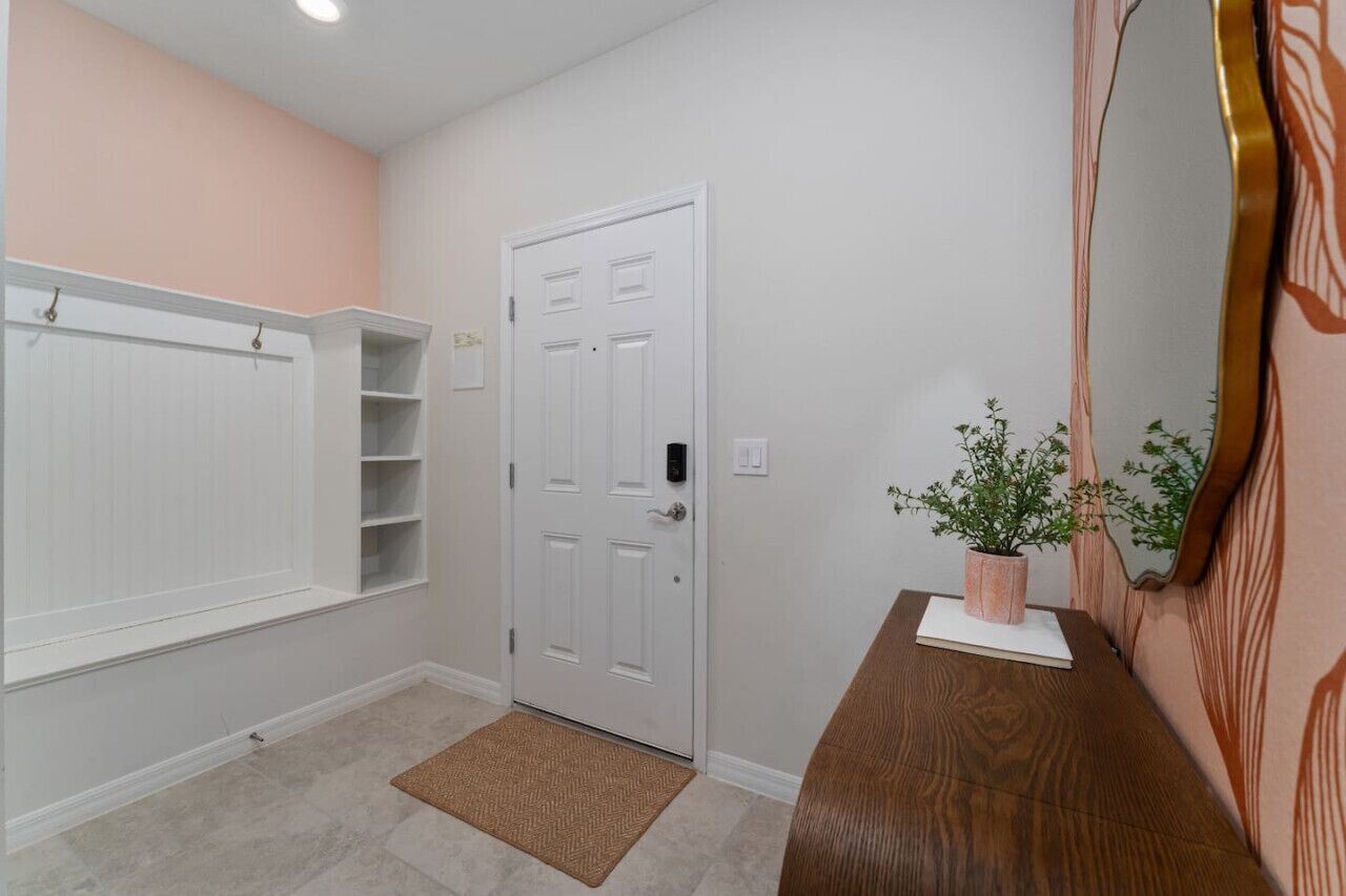 A hallway with a white door, a wooden bench, and a potted plant.