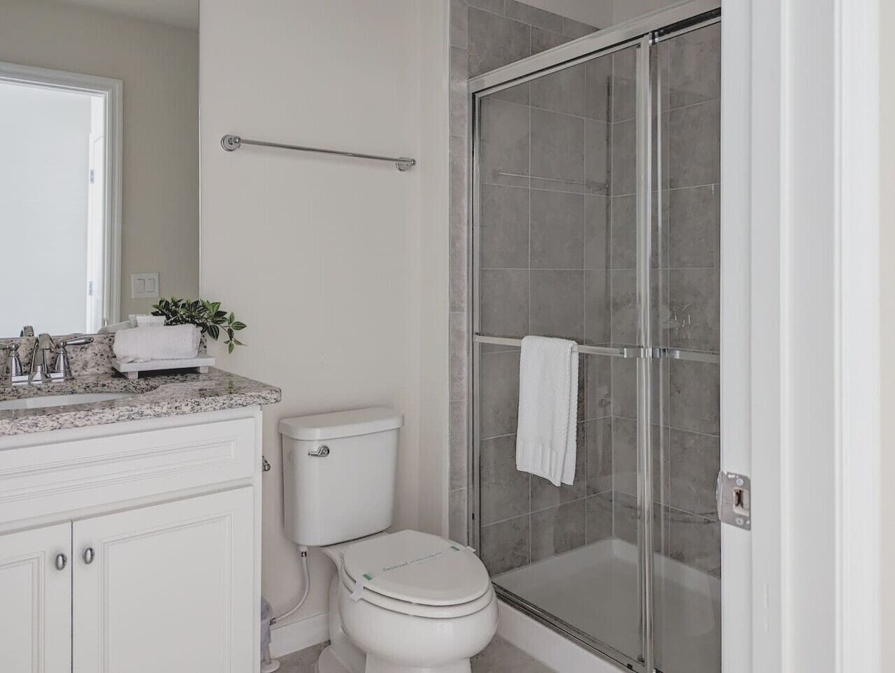 A bathroom with a white toilet, a glass shower enclosure, and a marble countertop with a sink and faucet.