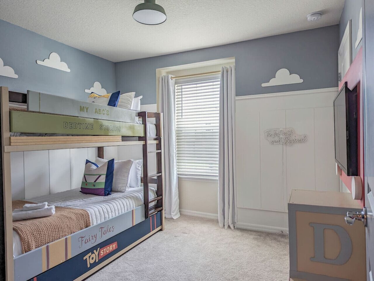 A child's bedroom with bunk beds, a wardrobe, and a window with curtains.
