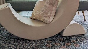 Una sala de estar moderna con un sofá curvo, dos sillones y una mesa de centro de vidrio.