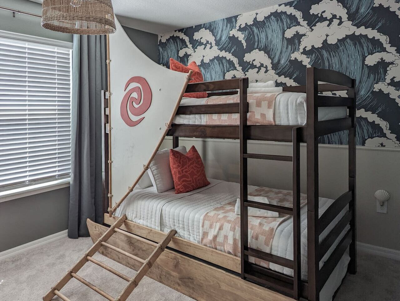 A bunk bed with a ladder, a decorative wall with a wave pattern, and a window with blinds.