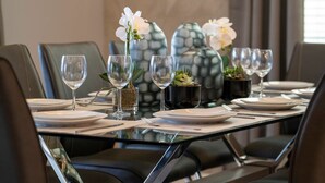 A dining table set with white plates, clear glasses, and a vase with white flowers. - 6BD InstaWorthy home pool cine and BBQ near Disney (Davenport)
