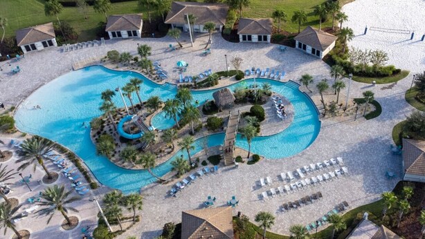 An aerial view of a resort with a large central pool, multiple smaller pools, and a variety of sun loungers and umbrellas. - 6BD InstaWorthy home pool cine and BBQ near Disney (Davenport)