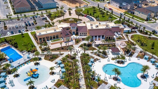 Eine Luftaufnahme eines Resorts mit mehreren Gebäuden, einem zentralen Pool und einer Wasserrutsche.