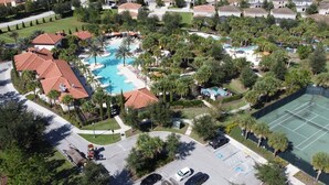 Vista aérea de una zona residencial con varias casas, piscina, canchas de tenis y estacionamiento.
