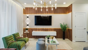Ein modernes Wohnzimmer mit einem grünen Sofa, einem weißen Couchtisch und einem großen Flachbildfernseher an der Wand.