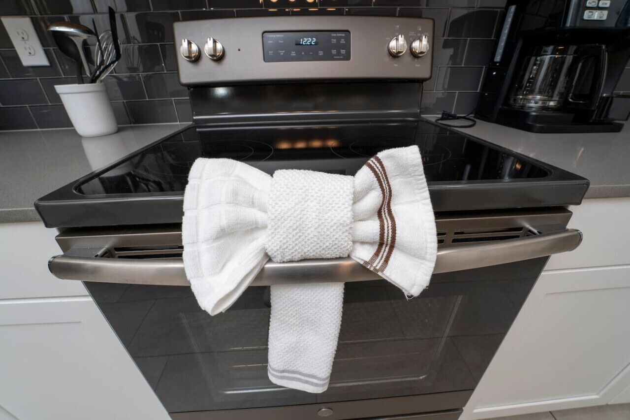 A kitchen with a stainless steel oven, a digital clock displaying 12:22, and a coffee maker on the counter.