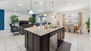 A modern kitchen with dark cabinetry, a granite countertop, and pendant lighting.