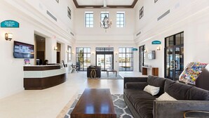 A spacious lobby with a reception desk, a comfortable seating area, and a chandelier.