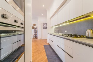 A modern kitchen with white cabinetry, a gas stove, and a built-in oven.