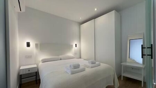 Une chambre à coucher moderne avec un grand lit, des tables de chevet et un miroir.