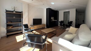 A modern living room with a sofa, a coffee table, a TV, and a bookshelf.