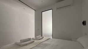A modern bedroom with a large bed, a bedside table, and a door.