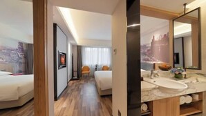 A hotel room with a bed, a desk, a chair, a bathroom with a sink and mirror, and a hallway with another room. - Pudong Fute Hotel (Xiepu Road Subway Station) (Shanghai)