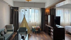 A hotel room with a sofa, a glass coffee table, a television, a bed, a small table with chairs, and a tent-like structure. - Pudong Fute Hotel (Xiepu Road Subway Station) (Shanghai)