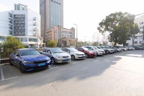 A parking lot with multiple cars parked in rows, buildings in the background, and a tree to the right. - Pudong Fute Hotel (Xiepu Road Subway Station) (Shanghai)