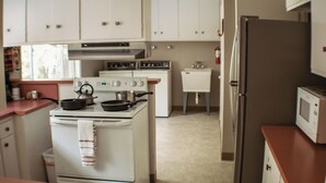 Eine Küche mit weißen Schränken, einem Herd, einer Spüle und einem Kühlschrank.
