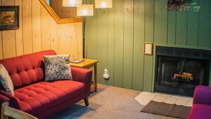 Una sala de estar acogedora con un sofá rojo, una mesita de madera y una pared verde con chimenea.